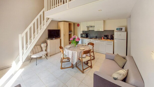 A compact living space with a dining area, kitchen, and a staircase leading to an upper level.