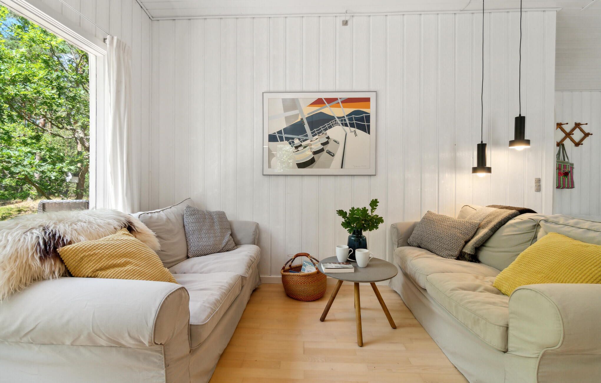 A cozy living room with two sofas, a small round table, and a framed artwork on the wall.