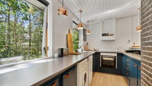 Een moderne keuken met een groot raam, een inbouwoven en een accentmuur van baksteen.