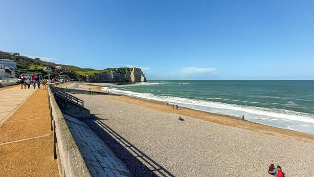 A coastal promenade with a pebble beach, a sea arch, and a promenade with people walking. - Beautiful home in étretat with WiFi (Étretat)