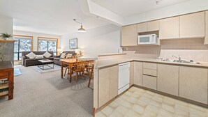 A modern kitchen with integrated dining area, large windows, and a built-in dishwasher. - Powderhorn by Whistler Premier (Whistler)