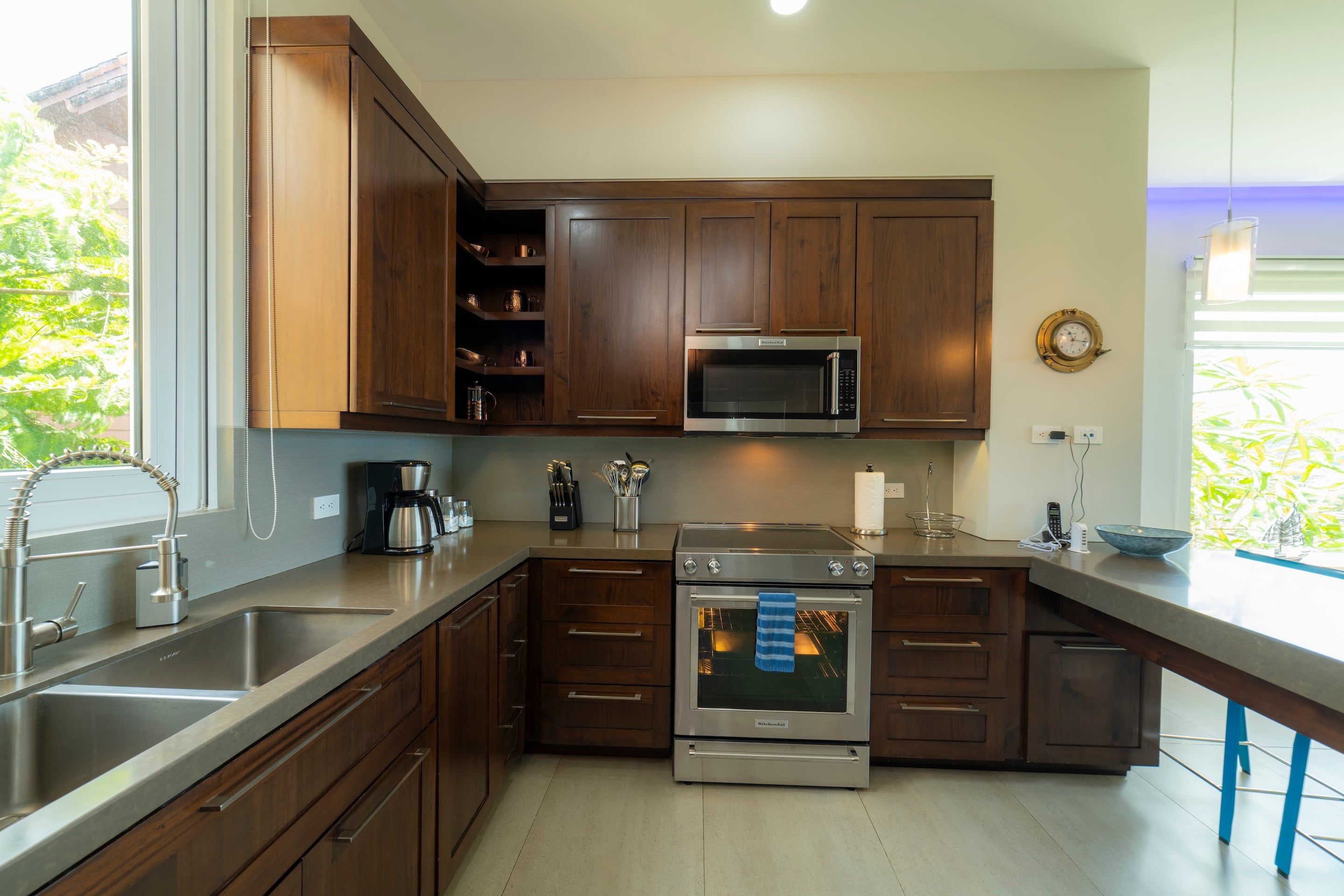 Una cocina moderna con armarios de madera, electrodomésticos de acero inoxidable y un amplio ventanal que proporciona luz natural.