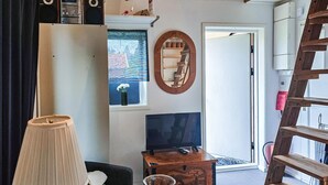 A living room with a TV, a lamp, a wooden cabinet, and a decorative mirror. - 1 bedroom amazing home in Blomstermåla (Blomstermåla)