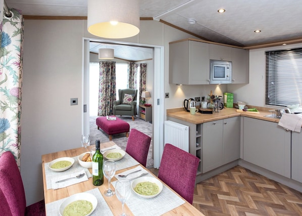 A compact kitchen with a dining area, a radiator, and a window with blinds.