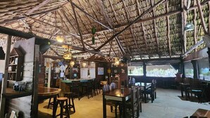 A rustic interior with a thatched roof, wooden furniture, and a bar area. - Playa Sonrisa Hotel (Xcalak)