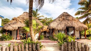 A resort with thatched-roof huts, palm trees, and a sandy pathway. - Playa Sonrisa Hotel (Xcalak)
