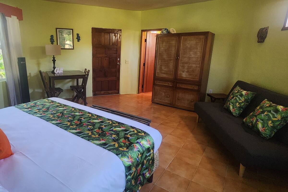 Una habitación con cama, sofá, mesa con lámpara y armario.