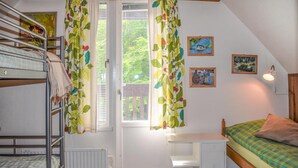 Un dormitorio con literas, un escritorio, una cama y una ventana con cortinas.