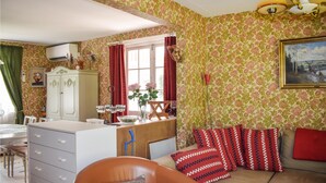 Una habitación con sofá, una mesa de comedor, un armario y un ventanal con cortinas.
