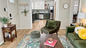 Un salón con un sofá verde, una mesa de centro de madera y una alfombra estampada.