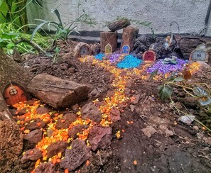Ein Miniatur-Garten mit einem gewundenen Pfad, kleinen Häusern und bunten Kieselsteinen.