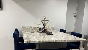 A modern dining area with a marble table, blue upholstered chairs, and a metal bar stool. - Cozy basement/studio apartment with kitchenette and bathroom! (Boston)