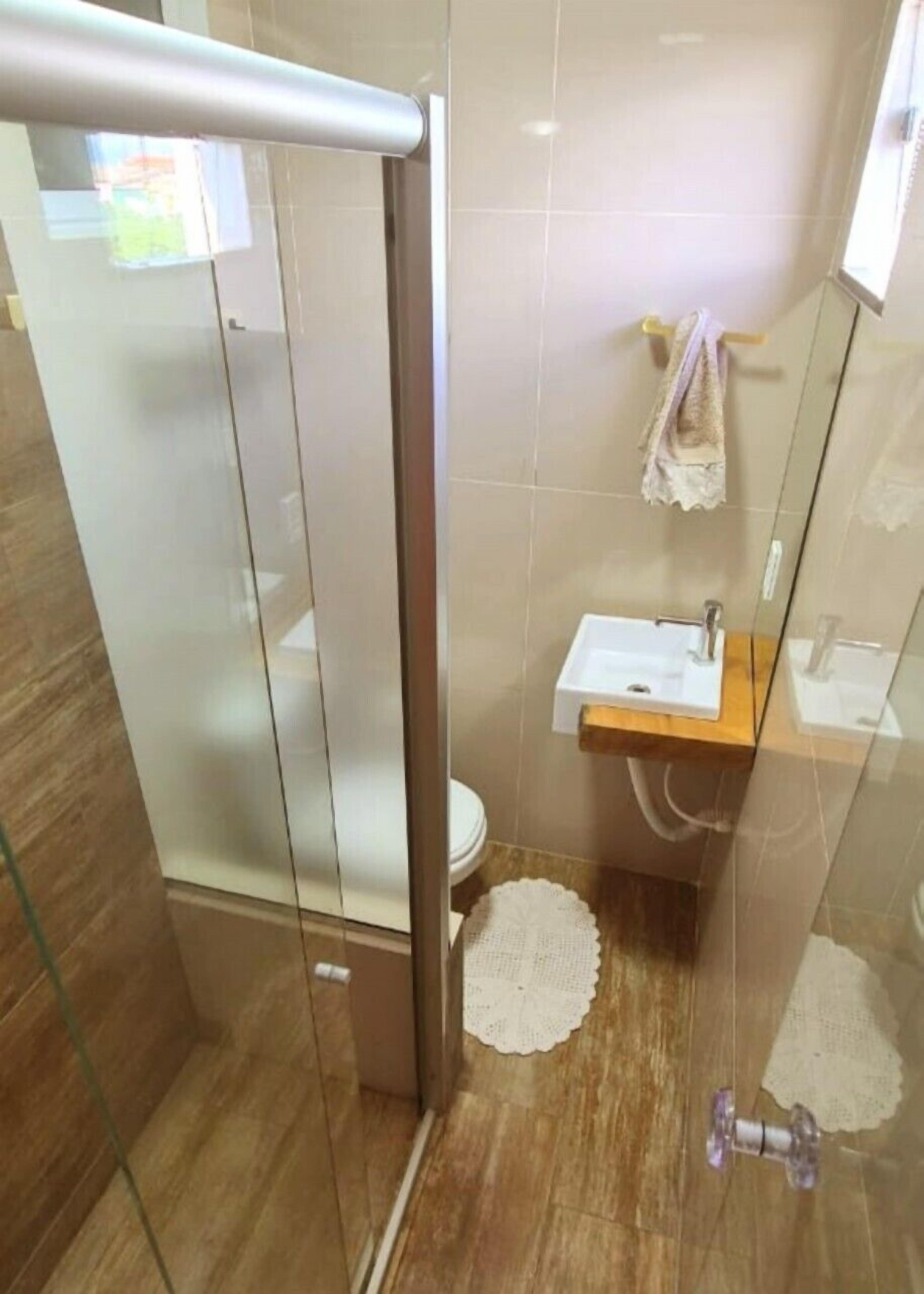 Un baño moderno con cabina de ducha de vidrio, tocador de madera y lavabo blanco.
