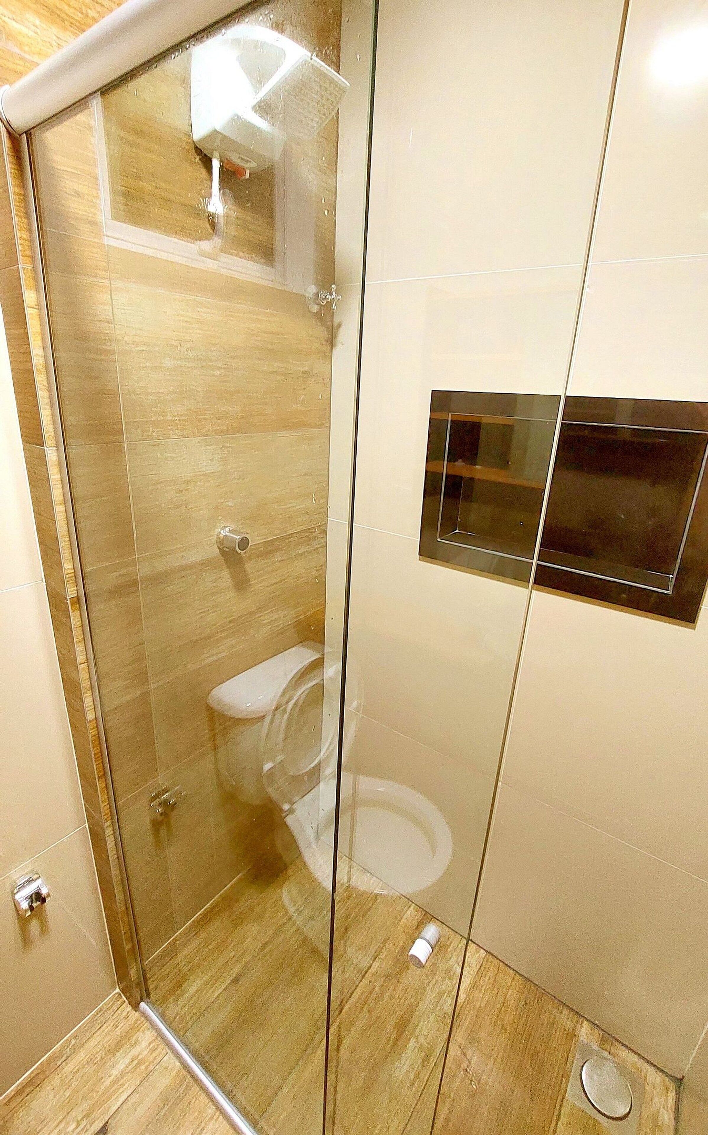 Un baño moderno con ducha envuelta en vidrio, inodoro y lavamanos empotrado.