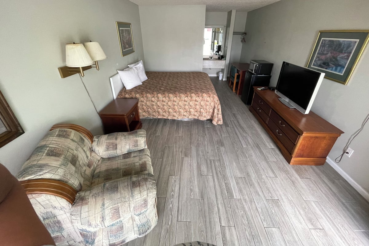 A hotel room with a bed, a sofa, a TV, and a desk.