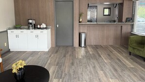 Eine moderne Küche mit Einbauherd, Kaffeemaschine und Spüle. In der Nähe der Spüle befindet sich ein Mülleimer und ein Blumentopf.
