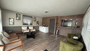 Ein modernes Wohnzimmer mit einer Couch, Sesseln, einem Couchtisch und einer Rezeption.