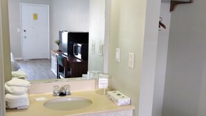 Ein Badezimmer mit einem beige gefärbten Waschbecken, einem großen Spiegel und einer weißen Mülleimer.