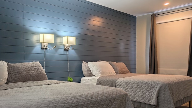 Ein Hotelzimmer mit zwei Betten, einer blauen Wand und einem Fenster mit Vorhängen.