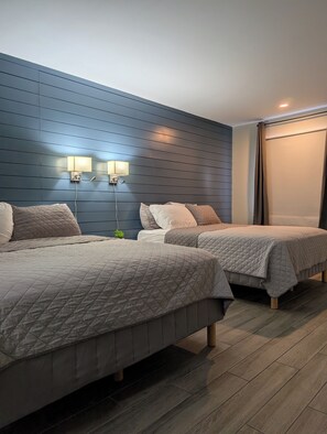 Ein Hotelzimmer mit zwei Betten, einer blauen Wand und einem Fenster mit Vorhängen.