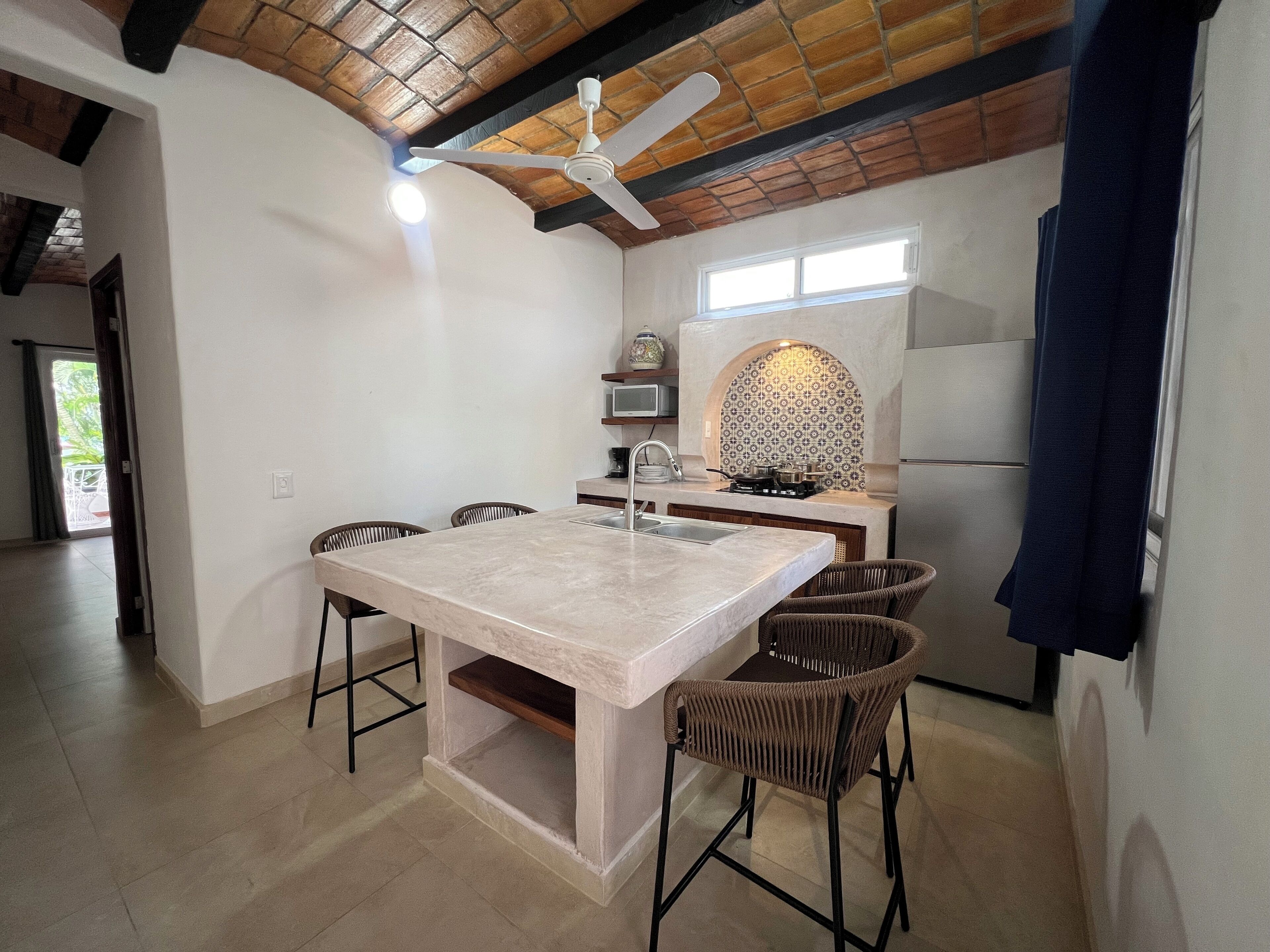 Une cuisine moderne dotée d’un îlot central, d’un ventilateur de plafond et d’un four encastré.