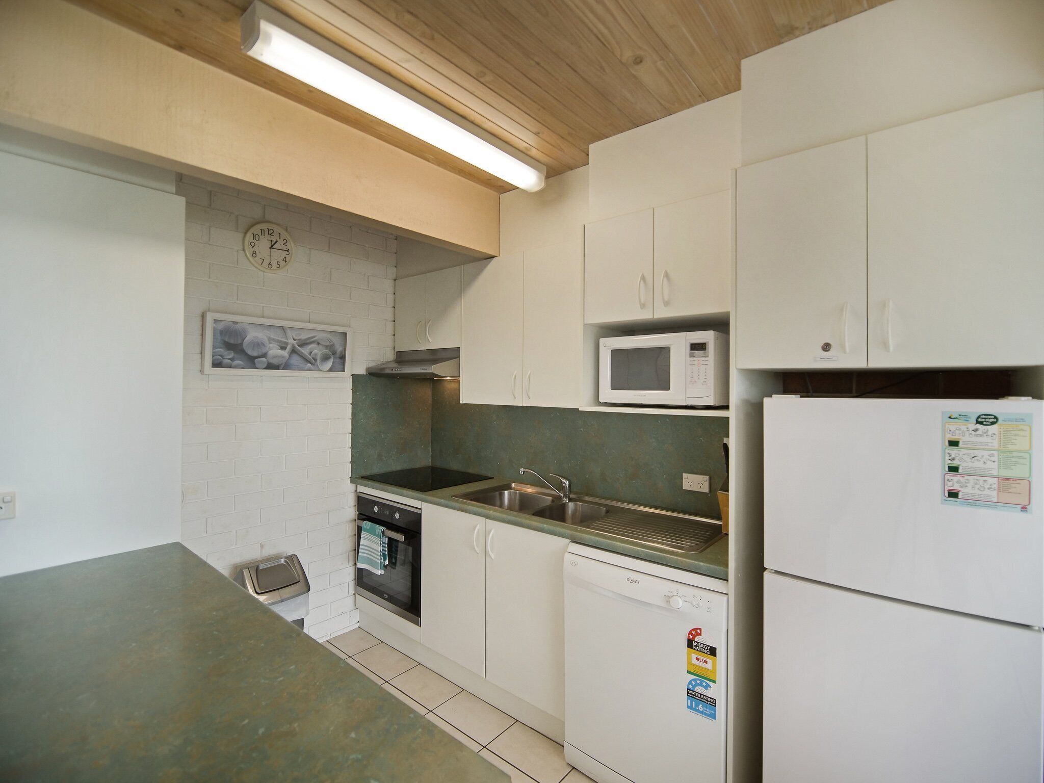 A compact kitchen with white cabinets, a microwave, a dishwasher, and a refrigerator.