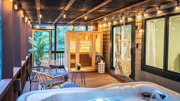 Bereich mit Whirlpool, Holzboden, Korbstühlen und einer Glastür zum Sauna-Bereich.