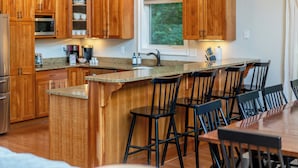Eine Küche mit Holzschränken, einer Granit Arbeitsplatte, einem Edelstahlkühlschrank, einer Mikrowelle und einer Kaffeemaschine.