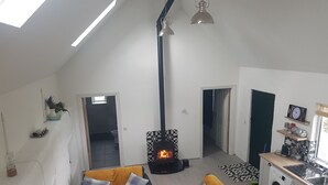 A spacious living area with a high ceiling, a fireplace, a sofa set, a coffee table, and a kitchen area with a washing machine. - Sleeps5-200yrFarmhouse-FreeParking-Garden (Tralee)