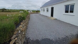 A white building with a gravel driveway, a stone wall, and a grassy field in the background. - Sleeps5-200yrFarmhouse-FreeParking-Garden (Tralee)