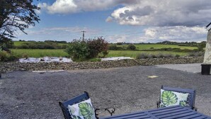 An outdoor seating area with a table and two chairs, set against a rural backdrop with fields and a stone wall. - Sleeps5-200yrFarmhouse-FreeParking-Garden (Tralee)