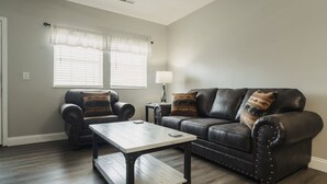 A living room with a dark leather sofa, two armchairs, a wooden coffee table, and a lamp. - EXCELLENT location!!  Walk to The Island. (Pigeon Forge)