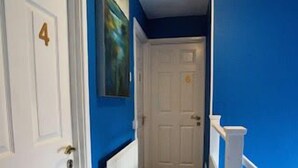 A hallway with a white door marked '4', a blue wall, and a white door at the end.