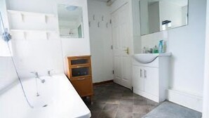 A bathroom with a white sink, mirror, and tiled floor.