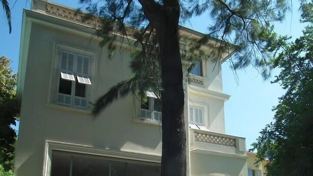 A two-story building with a large tree in the foreground.