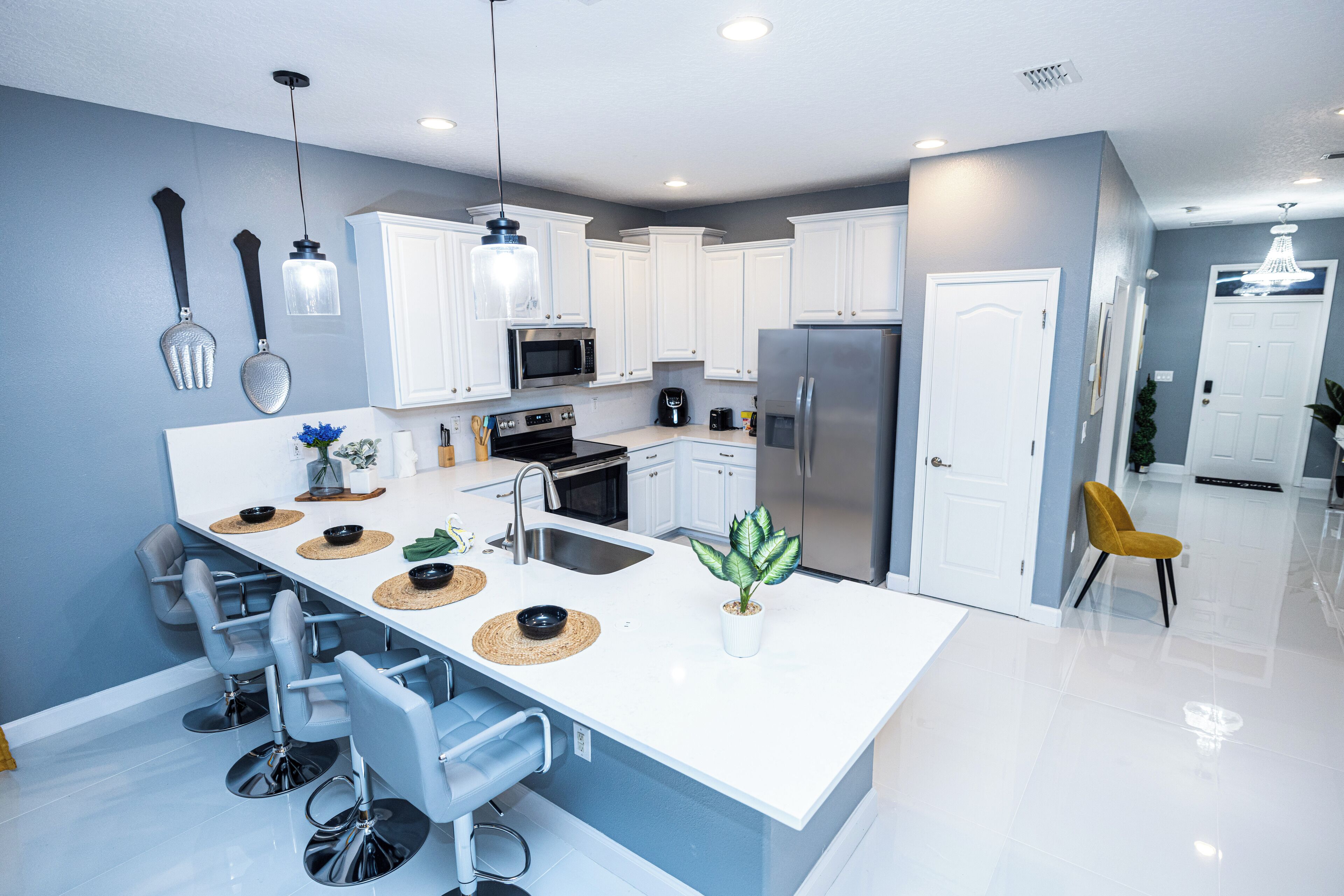 A modern kitchen with white cabinets, stainless steel appliances, and a central island with bar stools.