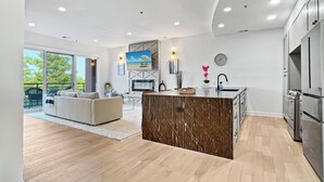 A modern kitchen with a marble island, stainless steel appliances, and a large window overlooking a balcony. - Luxury 2Bed w/ Amazing Views (Cornelius)