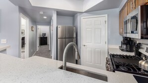 A modern kitchen with a stainless steel refrigerator, a gas stove, and wooden cabinets. - KING Beds, Heated Community Pool! 3 miles from Cardinal Stadium! (Phoenix)