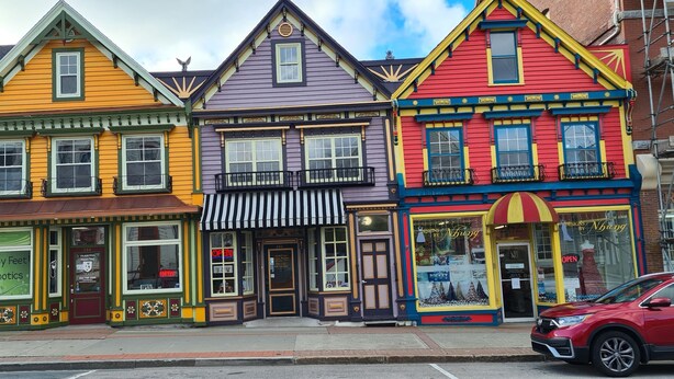 A row of colorful, historic buildings with storefronts, including a visible sign for Happy Feet Orthotics. - Coastal Charm by the Bay: 4 Bedroom Apartment next to Yarmouth CAT Ferry (Yarmouth)