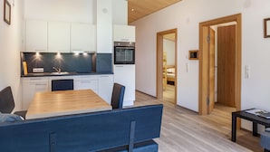 Eine moderne Küche mit weißen Schränken, einem Holztisch und einem eingebauten Backofen.