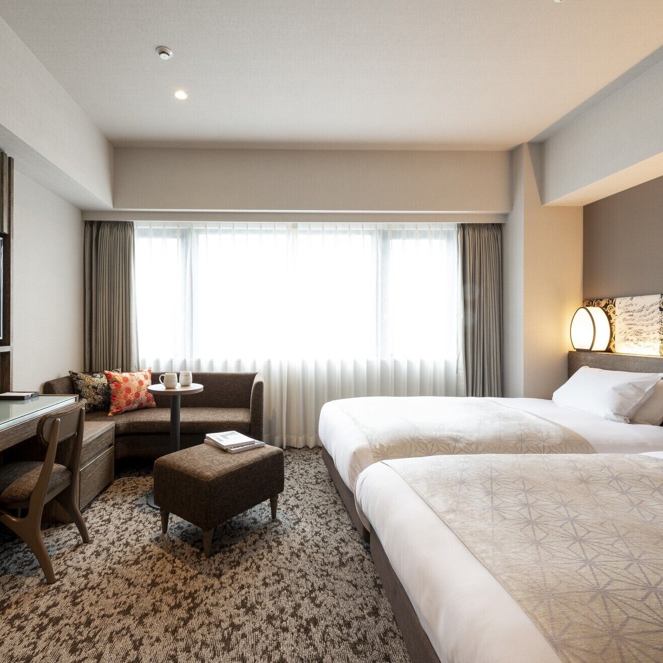 Quarto de hotel com uma cama, um sofá, uma escrivaninha e uma mesinha.