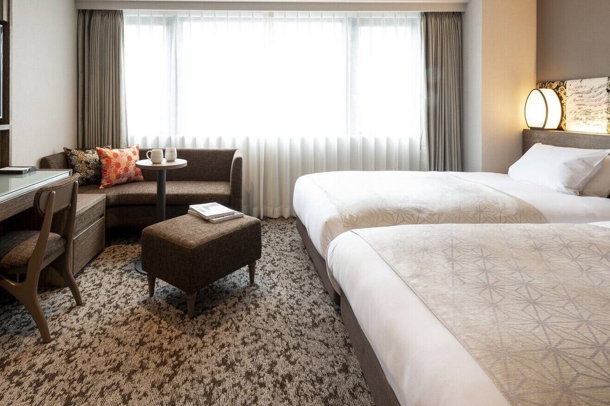 A hotel room with a bed, a sofa, a desk, and a small table.