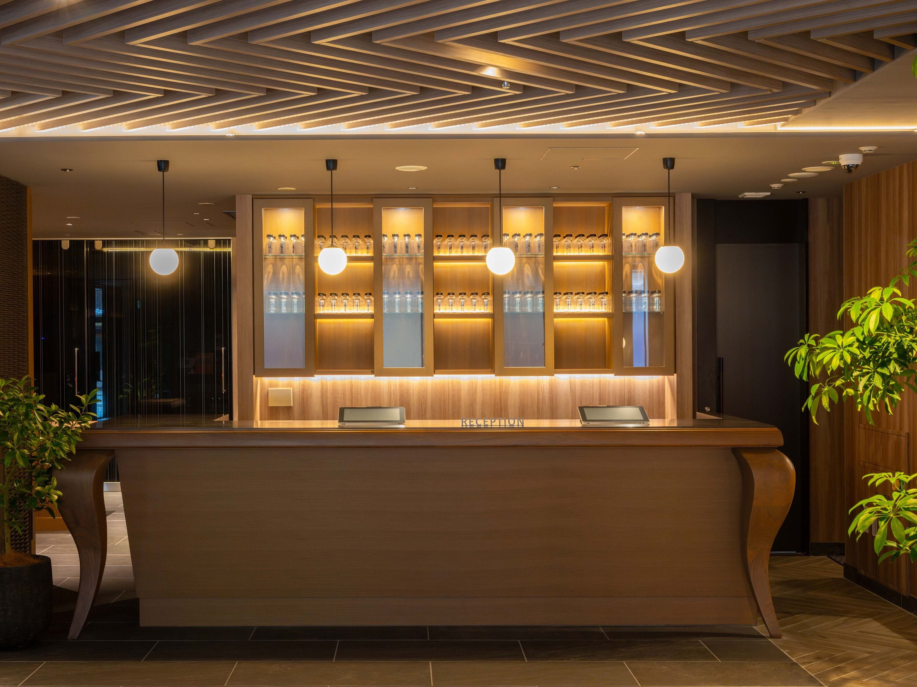 A reception desk with a modern design, featuring a wooden panel backdrop and pendant lighting.