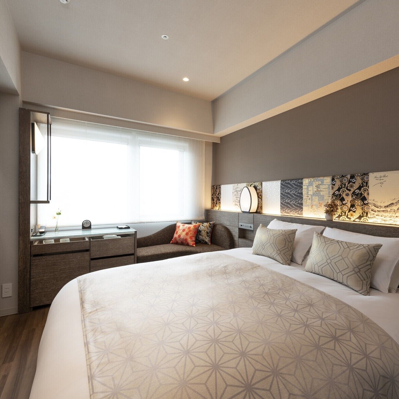 Quarto de hotel moderno com uma cama grande, uma mesa e uma janela.