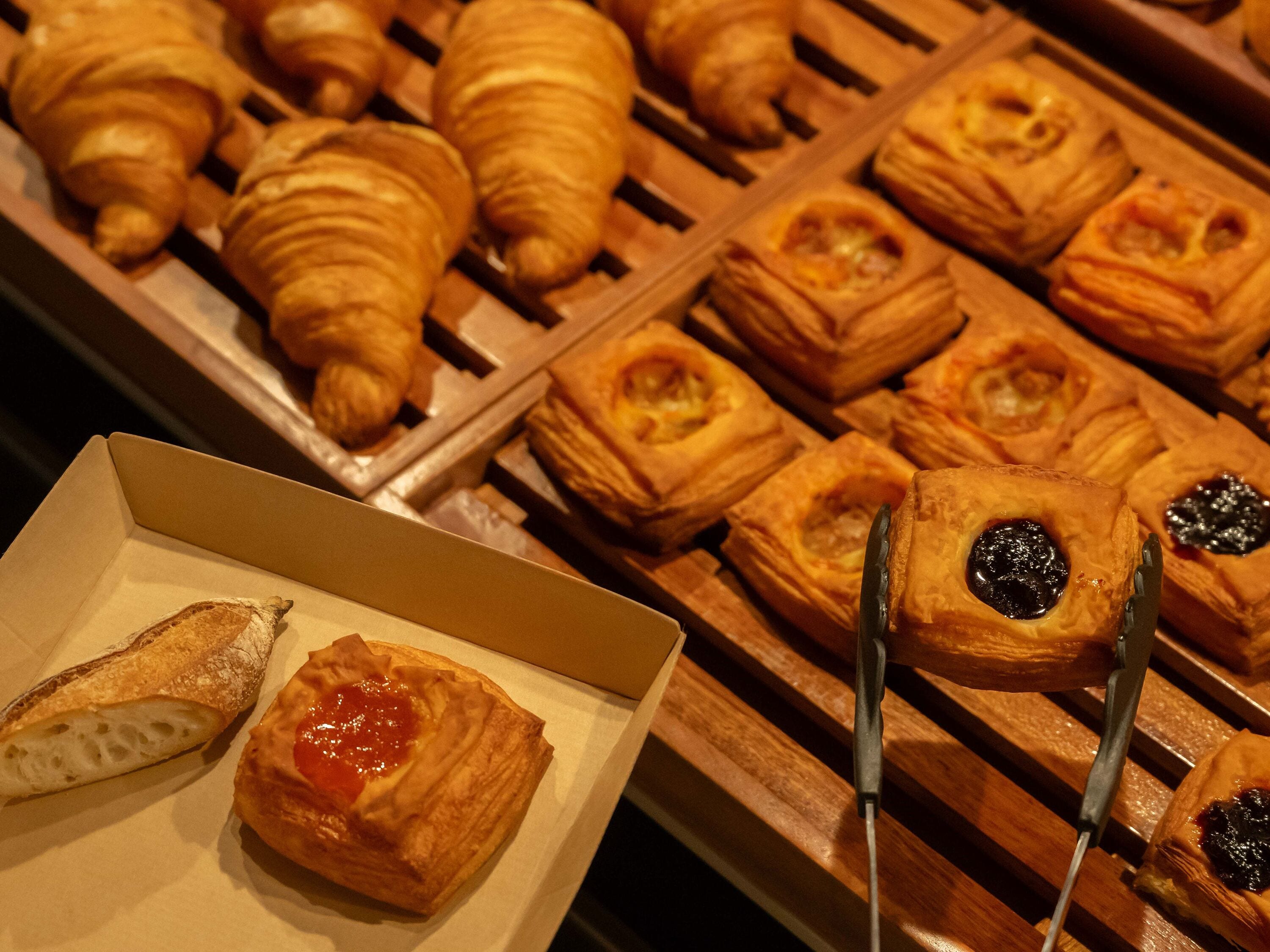 A variety of pastries including croissants and puff pastries arranged on a wooden rack.