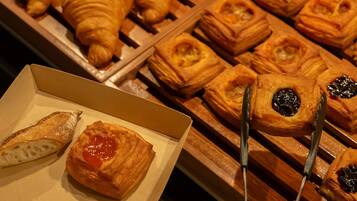 A variety of pastries including croissants and puff pastries arranged on a wooden rack.