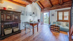 A spacious room with a wooden ceiling, a dining table with chairs, a sofa, and a fireplace.