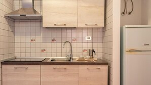 Une cuisine avec des meubles de couleur bois clair, un évier en acier inoxydable et un réfrigérateur blanc.