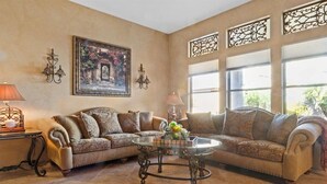 Un salon avec un canapé beige, une table basse en verre et des appliques murales décoratives.