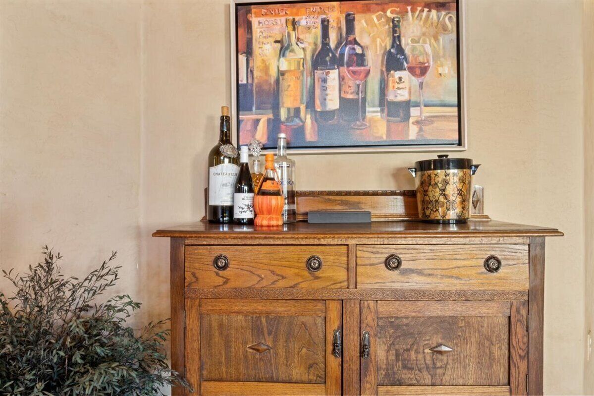 A wooden cabinet with bottles and a wine glass on top.